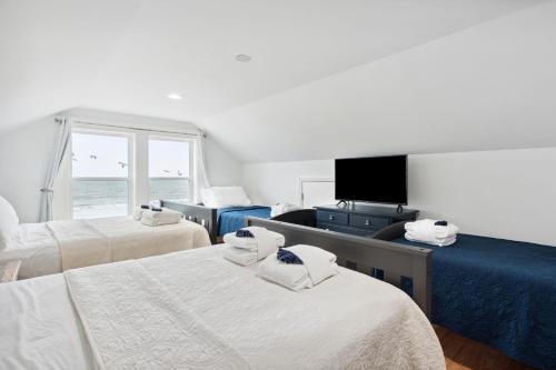 a bedroom with two beds and a tv and a window at Oceanfront w Pool Panoramic Deck Views 5BDR Folly Ocean Breeze by AvantStay in Folly Beach
