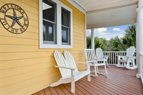 a porch with white chairs and a clock on a house at Oceanfront w Pool Panoramic Deck Views 5BDR Folly Ocean Breeze by AvantStay in Folly Beach