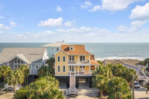 a house on the beach with the ocean in the background at Oceanfront w Pool Panoramic Deck Views 5BDR Folly Ocean Breeze by AvantStay in Folly Beach