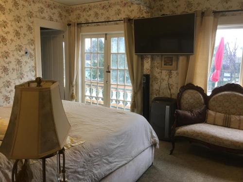 a bedroom with a bed and a chair and a flat screen tv at Haterleigh Heritage Inn in Victoria