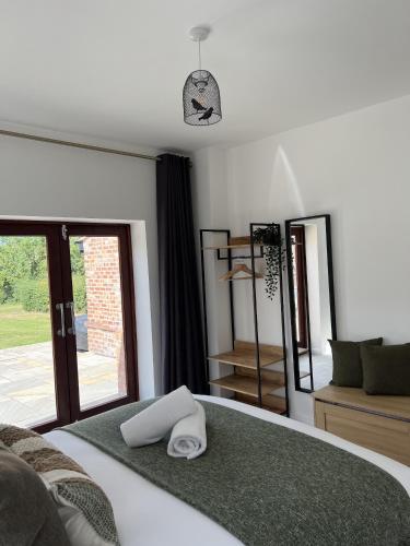 a bedroom with a bed with two towels on it at No1 Little Barrow Barns - Sleeps 10 in Chester