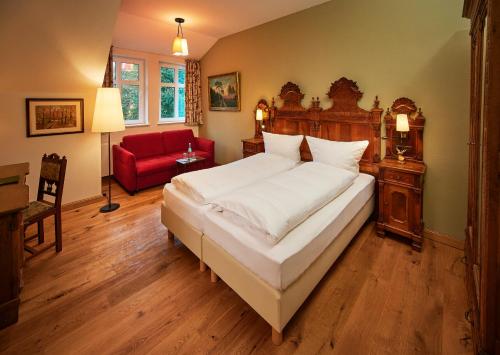 a bedroom with a large bed and a red chair at Hotel Anno 1848 in Lindern