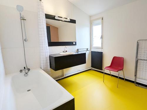 La salle de bains est pourvue d'une baignoire blanche et d'une chaise rouge. dans l'établissement Xanadu - Maison Design 80, à Rochefort