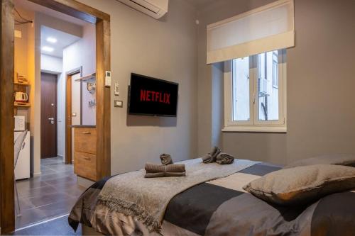 a bedroom with a bed with a television on the wall at Netflix & Wi-Fi Suite Trieste - NewYork Dream in Trieste