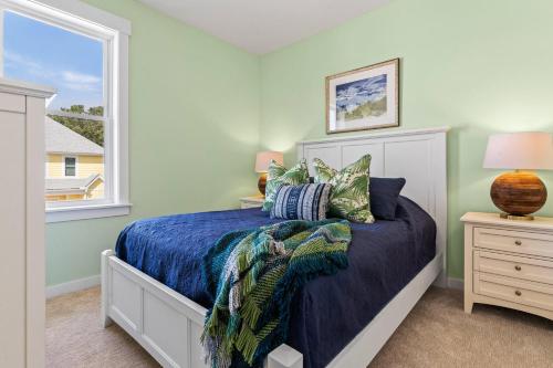 a bedroom with a bed with blue sheets and a window at Cambridge Reserve at Bermuda Bay by KEES Vacations in Kill Devil Hills
