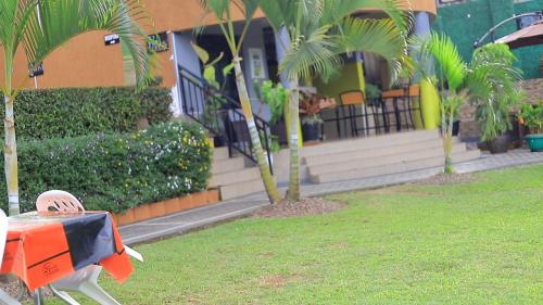 a house with palm trees in front of a yard at Rustic Gardens Bed & Breakfast Kitunzi Lungujja in Kampala