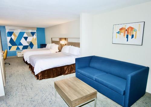 a hotel room with two beds and a blue couch at Holiday Inn Express Hotel & Suites St. Charles by IHG in St. Charles