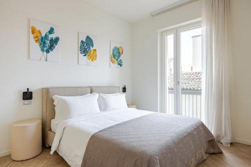a white bedroom with a large bed and a window at Appartamento Louis in Verona
