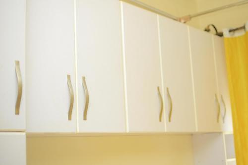 a kitchen with white cabinets and a yellow curtain at Rustic Gardens Bed & Breakfast Kitunzi Lungujja in Kampala