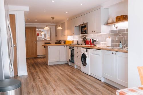 a kitchen with white cabinets and a washer and dryer at Riverbank Cottage in Ironbridge