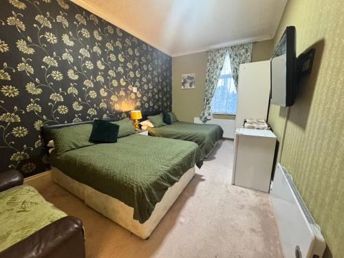 a small bedroom with two beds and a tv at The Holmlea in Blackpool