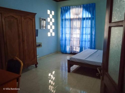 a bedroom with a bed and a window with blue walls at Villa Bandara in Pannipitiya