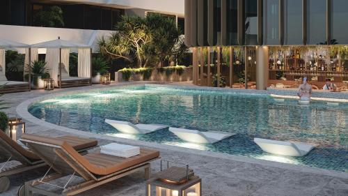 a large swimming pool with lounge chairs in a building at voco Gosford by IHG in Gosford