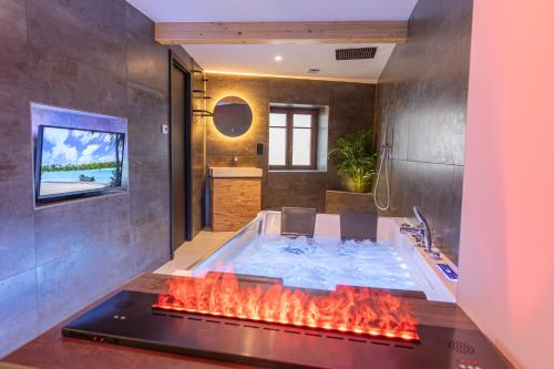 a bathroom with a hot tub with a fireplace at Haut Koeur du Château in Saint-Hippolyte