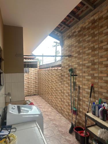 a bathroom with a toilet and a brick wall at Casa Itanhaém Multicultural in Itanhaém