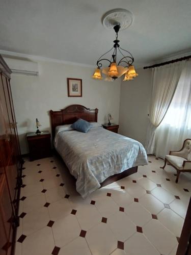 a bedroom with a bed and a chandelier at Merino Casa Rural in Yunquera
