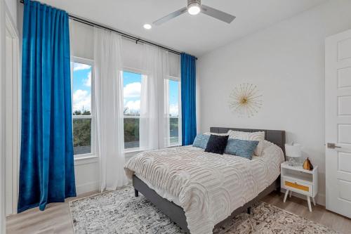 a bedroom with a bed with blue curtains and a window at Pet-Friendly 2BR l Private Baths l Stylish Stay in Dallas