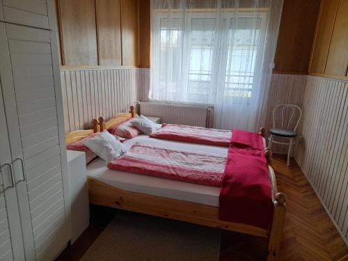 a bedroom with a bed with red and white sheets at Anatan Apartmanok Harkány in Harkány