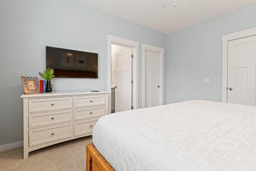 a white bedroom with a bed and a flat screen tv at Cambridge Reserve at Bermuda Bay by KEES Vacations in Kill Devil Hills
