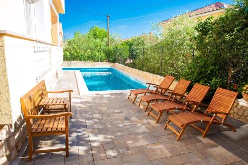 Un grupo de sillas junto a una piscina. en Pension Tina App 1, en Šilo