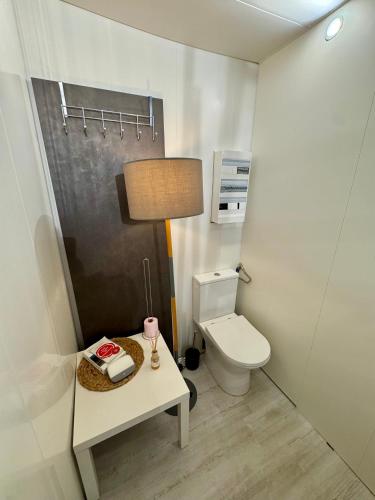 a bathroom with a toilet and a table with a lamp at Un repos au cœur du Périgord vert in Varaignes