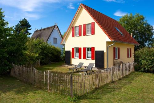 a white house with red windows and a fence at Familienurlaub Im Haus Nemo in Gramkow