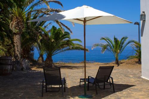 加拉奇科Haus Am Meer In Garachico的海滩上一把遮阳伞下的两把椅子