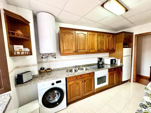 a kitchen with wooden cabinets and a washer and dryer at Apartamento La Magdalena Selnatur in Llanes
