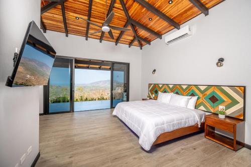 a bedroom with a bed and a flat screen tv at Villa cielo y mar azul in Cuajiniquil