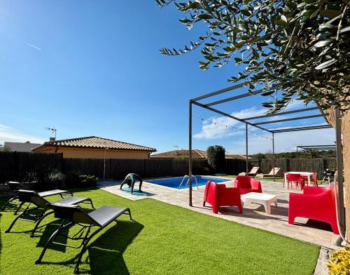 ein Garten mit Pool, roten Stühlen und einem Tisch in der Unterkunft Modernes Einfamilienhaus mit privatem Pool Villa Medes Mar in l'Estartit - b52678 in Torroella de Montgrí