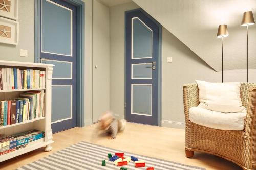 a child playing in a room with a book shelf and a chair at Haus Möwennest in Midlum