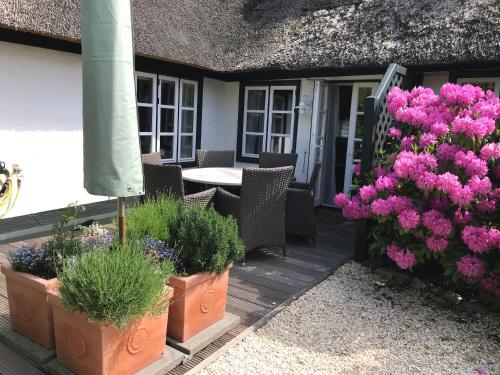 a patio with flowers and a table and chairs at Haus Möwennest in Midlum