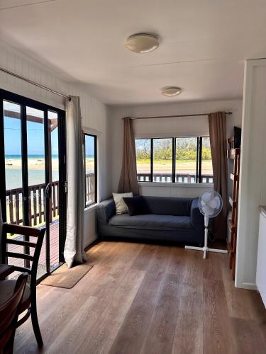 a living room with a couch and some windows at The Beach Arrawarra in Arrawarra