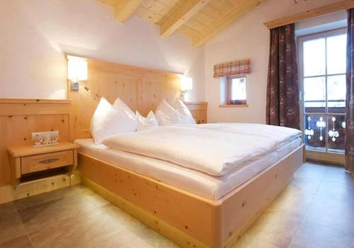 a bedroom with a large bed with a wooden headboard at Ferienhaus Wallegg Lodge In Saalbach Hinterglemm in Saalbach Hinterglemm