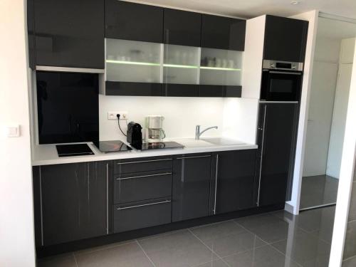 une cuisine avec des armoires noires et blanches et un évier dans l'établissement Résidence Héliopolis Bâtiment E - Studio 2 pers. HELIOPOLIS E MAE-4594, au Cap d'Agde