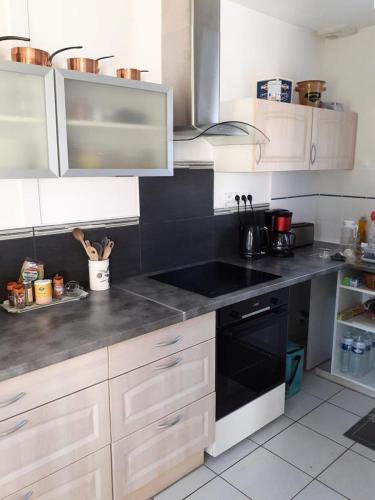 La cuisine est équipée de placards blancs et d'un évier noir. dans l'établissement Résidence Closerie De Margot - 019 - Environnement calme pour cette maison pouvant accueillir 4 personnes MAE-4341, à Soulac-sur-Mer