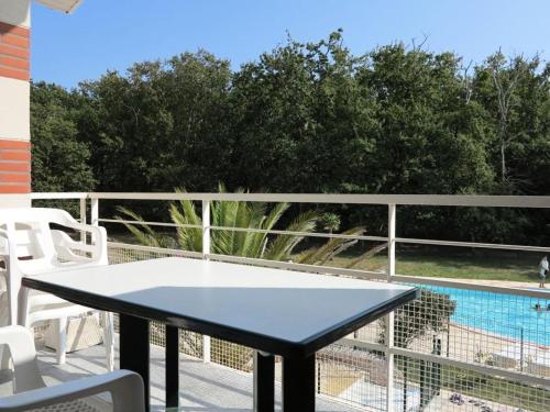 - une table sur un balcon avec vue sur la piscine dans l'établissement Résidence Domaine Des Sables - 015 - Vivez en pleine nature à deux pas de l'Océan MAE-4511, à Soulac-sur-Mer