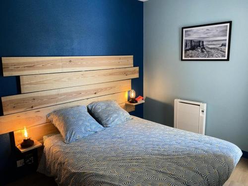une chambre avec un lit avec un mur bleu dans l'établissement Résidence Domaine Des Sables - 015 - Vivez en pleine nature à deux pas de l'Océan MAE-4511, à Soulac-sur-Mer