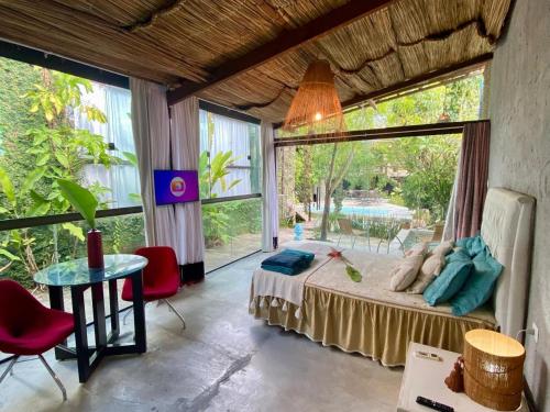 a bedroom with a bed and a table and windows at Studio Bali - Village Capixaba in Gravatá