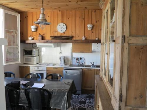 une cuisine avec une table, des chaises et une horloge dans l'établissement Résidence 086-soulac Sur Mer - 086 - Très belle villa Soulacaise au calme et sans vis à vis MAE-4481, à Soulac-sur-Mer
