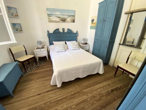 une chambre avec un lit bleu et deux chaises dans l'établissement Résidence 086-soulac Sur Mer - 086 - Très belle villa Soulacaise au calme et sans vis à vis MAE-4481, à Soulac-sur-Mer