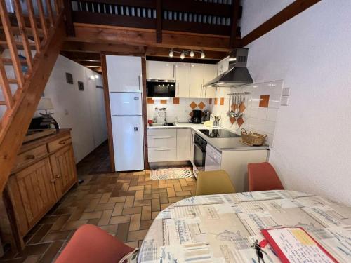 Il comprend une cuisine avec une table et un réfrigérateur blanc. dans l'établissement Résidence Hameau De L'amélie - 051 - Agréable maisonnette au Hameau de l'Amélie MAE-8851, à Soulac-sur-Mer
