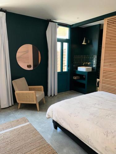 une chambre avec un lit, une chaise et un miroir dans l'établissement Résidence 023-soulac Sur Mer - 023 - Magnifique villa en duplex avec piscine en plein cœur de la station de Soulac/mer MAE-6041, à Soulac-sur-Mer