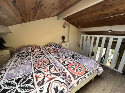 une chambre avec un lit avec une couette colorée dans l'établissement Résidence Hameau De L'amélie - 053 - Jolie maisonnette classée 3 au Hameau de l'Amélie MAE-6091, à Soulac-sur-Mer
