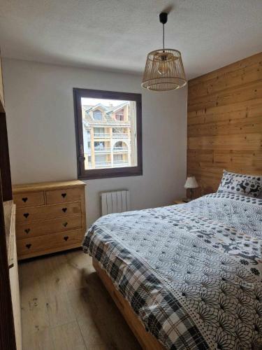 une chambre avec un lit, une commode et une fenêtre dans l'établissement Joli appartement rénové et garage proche cabines Pontillas, à La Salle Les Alpes