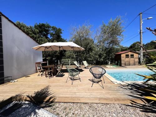 - une terrasse en bois avec des chaises et un parasol à côté de la piscine dans l'établissement Résidence 008-soulac Sur Mer - 008 - Jolie villa contemporaine avec piscine MAE-6151, à Soulac-sur-Mer