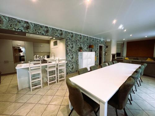 a kitchen and dining room with a white table and chairs at Villa 114 with heated pool in Ploegsteert