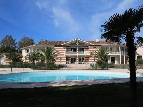 une grande maison avec une piscine devant dans l'établissement Résidence Domaine Des Sables - 036 - Maison mitoyenne dans un domaine de vacances avec piscine MAE-3581, à Soulac-sur-Mer