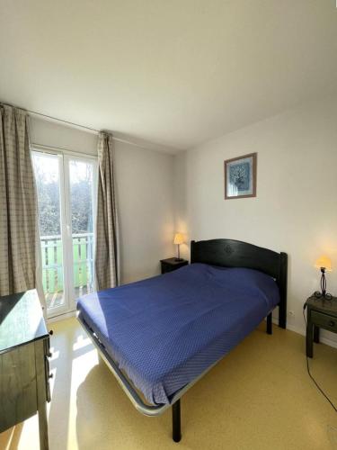 une chambre avec un lit avec des draps bleus et une fenêtre dans l'établissement Résidence Domaine Des Sables - 037 - Agréable maison mitoyenne dans une résidence de vacances 3 étoiles MAE-3601, à Soulac-sur-Mer