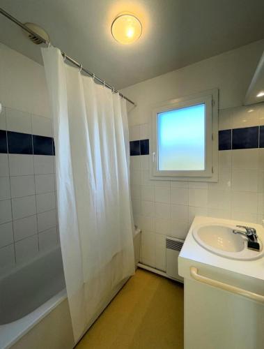 La salle de bains est pourvue d'un rideau de douche blanc et d'un lavabo. dans l'établissement Résidence Domaine Des Sables - 037 - Agréable maison mitoyenne dans une résidence de vacances 3 étoiles MAE-3601, à Soulac-sur-Mer